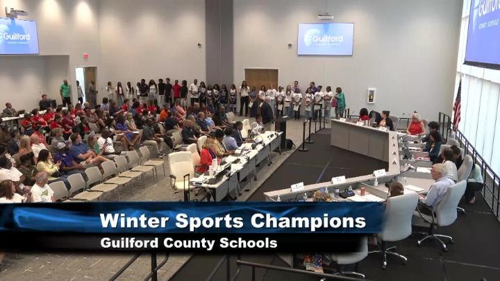 Wide shot of Guilford County Schools board room showing board members, staff and meeting attendees
