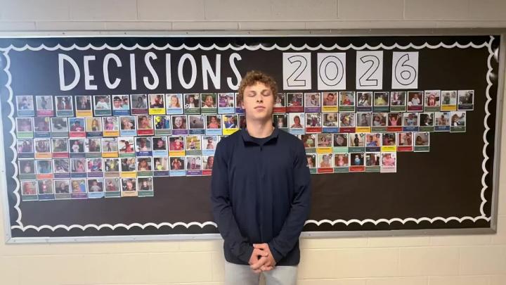 Northwest H.S. senior stands in front of Decision Day 2026 bulletin board