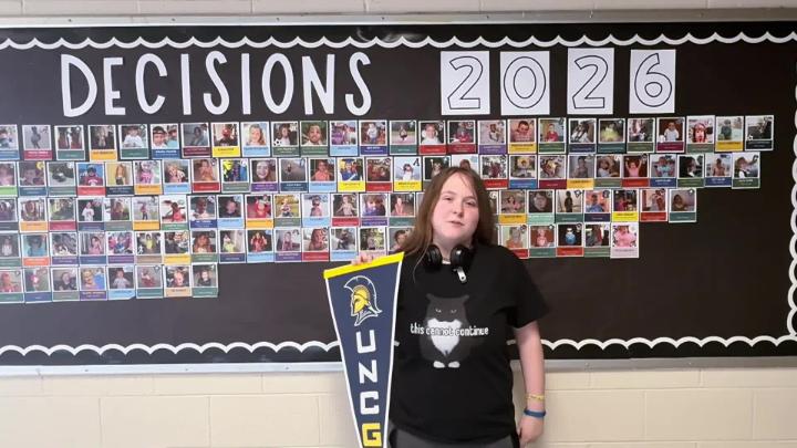 Northwest H.S. senior stands in front of Decision Day 2026 bulletin board