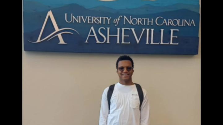 STEM Early College at NC A&T senior standing in front of a blue UNC Asheville sign