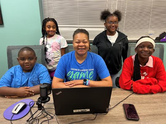 Mrs. Satterwhite and four Falkener Elementary Students pose at school news desk